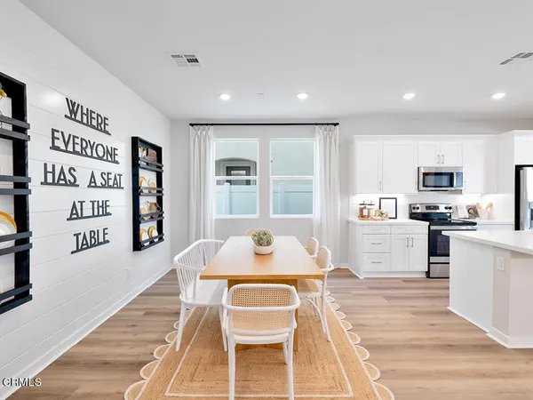 a living room with stainless steel appliances furniture and a kitchen view