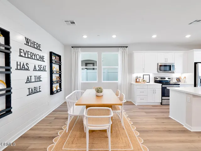 a living room with stainless steel appliances furniture and a kitchen view
