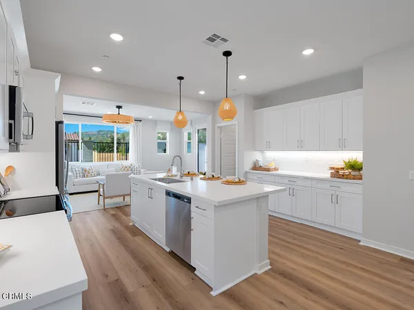 a kitchen with stainless steel appliances kitchen island granite countertop a sink a stove and a wooden floors