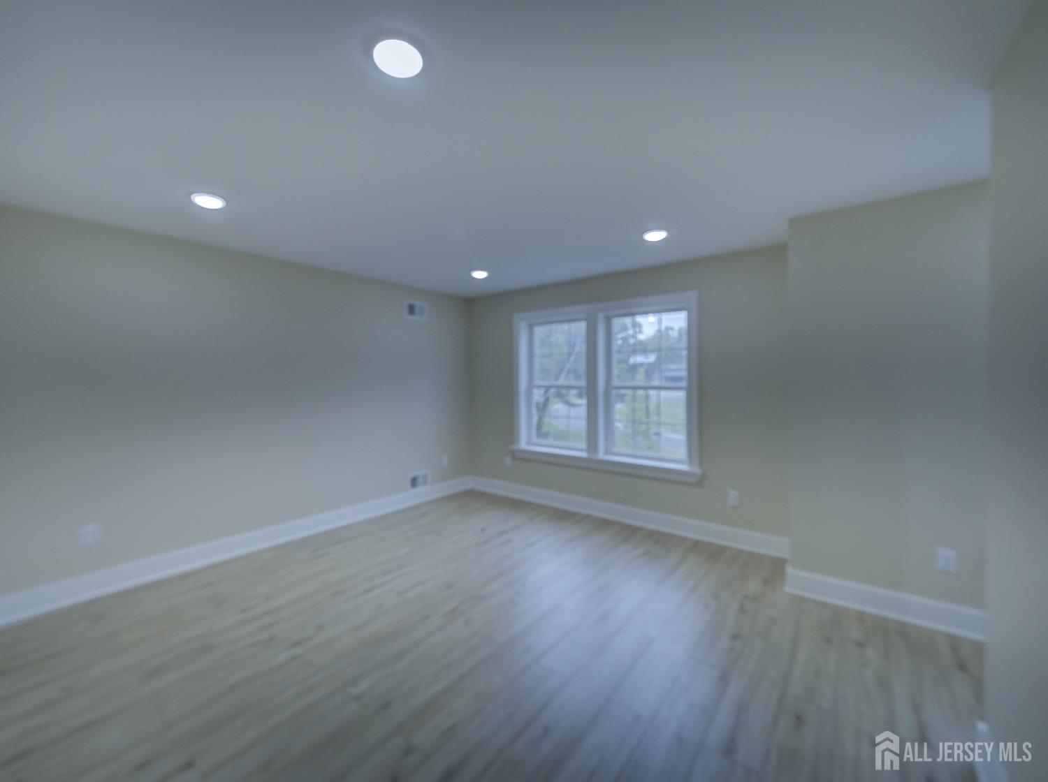 8 Travers Avenue, Unit 1 Edison, NJ 08817 - Photo 9 of 19 an empty room with wooden floor and windows