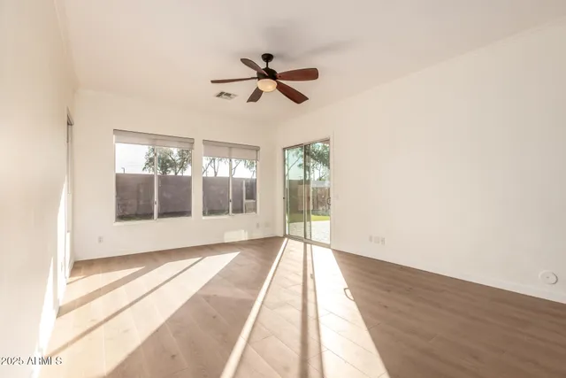 a view of empty room with wooden floor and fan