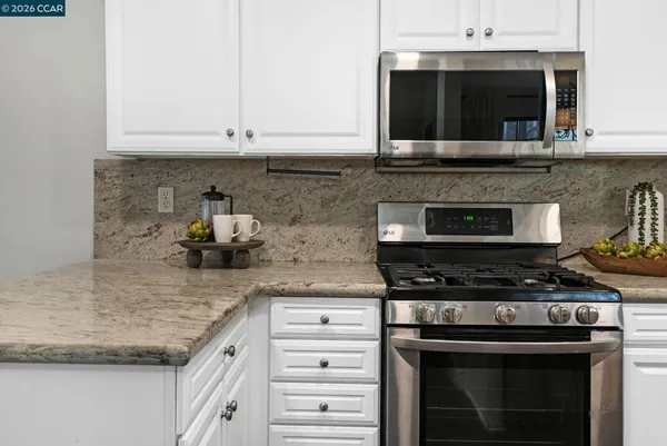 a kitchen with granite countertop a stove and a white cabinets