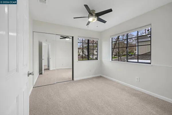 a view of an empty room with a window and a ceiling fan