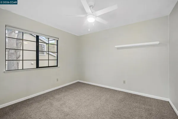 an empty room with windows and fan