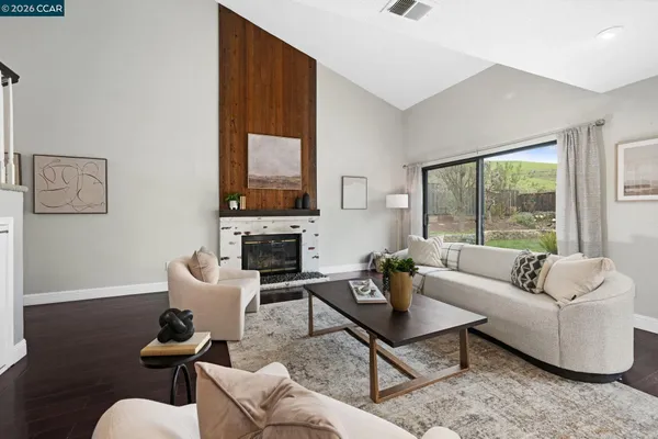a living room with furniture a fireplace and a floor to ceiling window