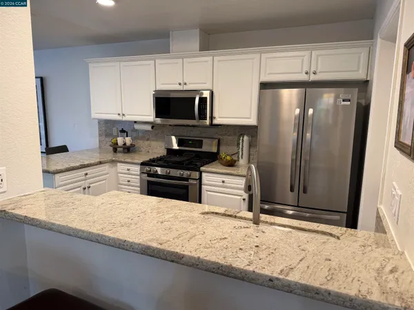 a kitchen with stainless steel appliances granite countertop a refrigerator a stove and a sink