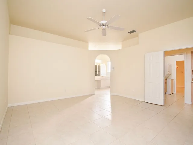 an empty room with a chandelier fan and windows