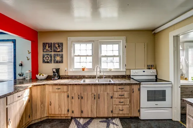 a kitchen with granite countertop a sink a stove and cabinets