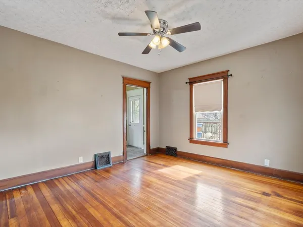 a view of an empty room with a window and wooden floor