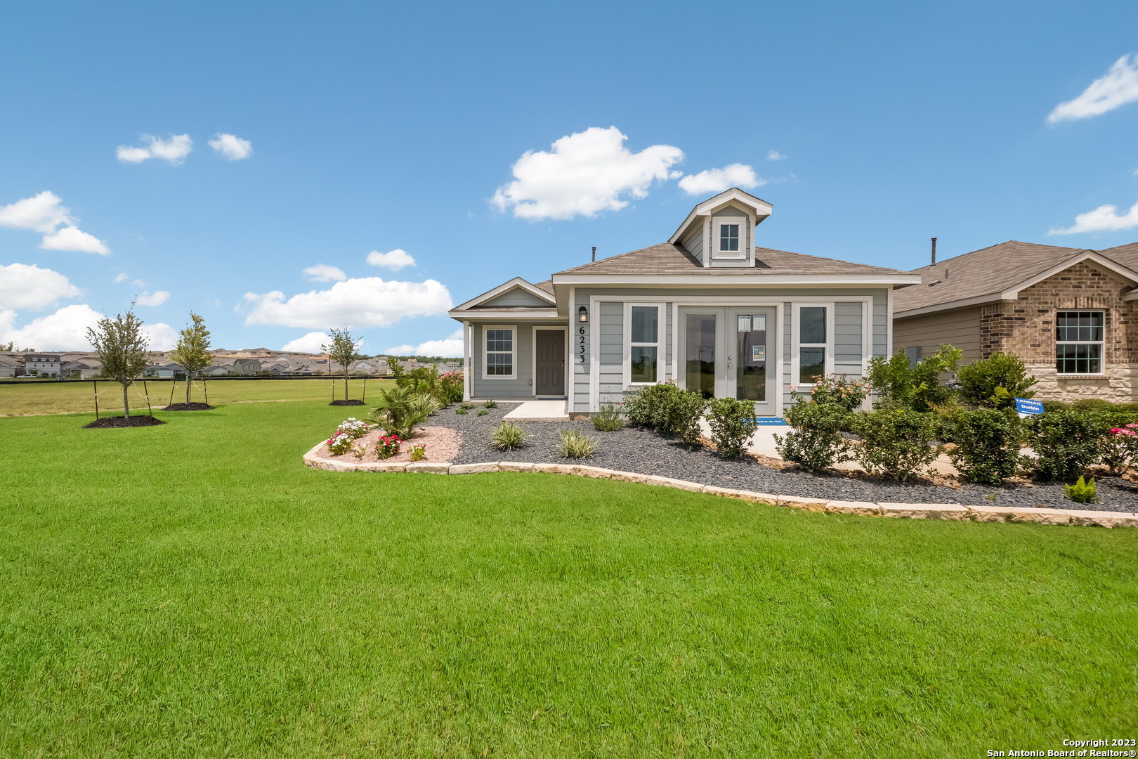 a front view of a house with garden and trees