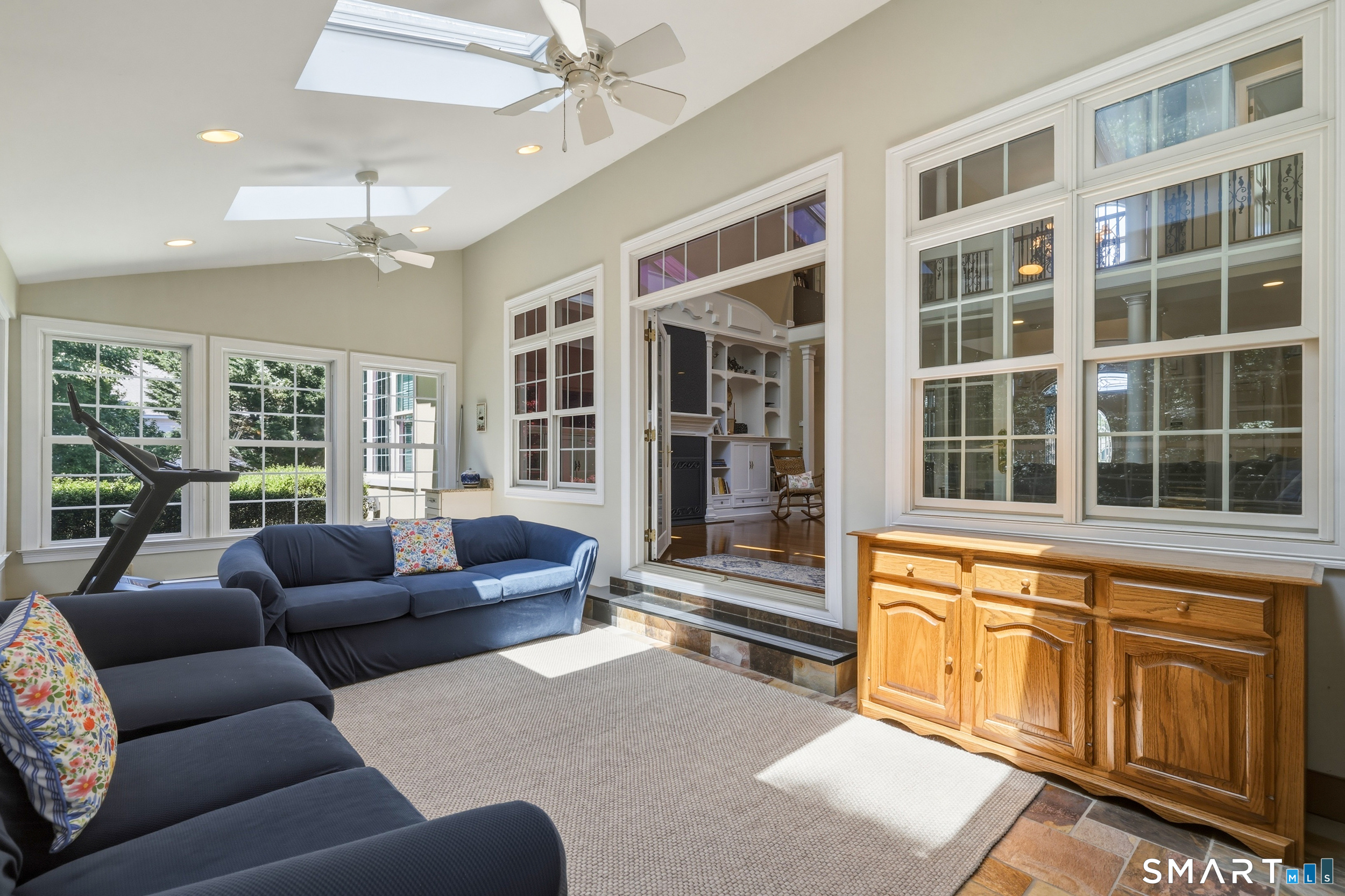 122 Lower Road Guilford, CT 06437 - Photo 20 of 40 An expansive year-round sunporch extends off the family room, featuring tile flooring, skylights, and ceiling fans. This light-filled space offers direct access to the back patio and yard.