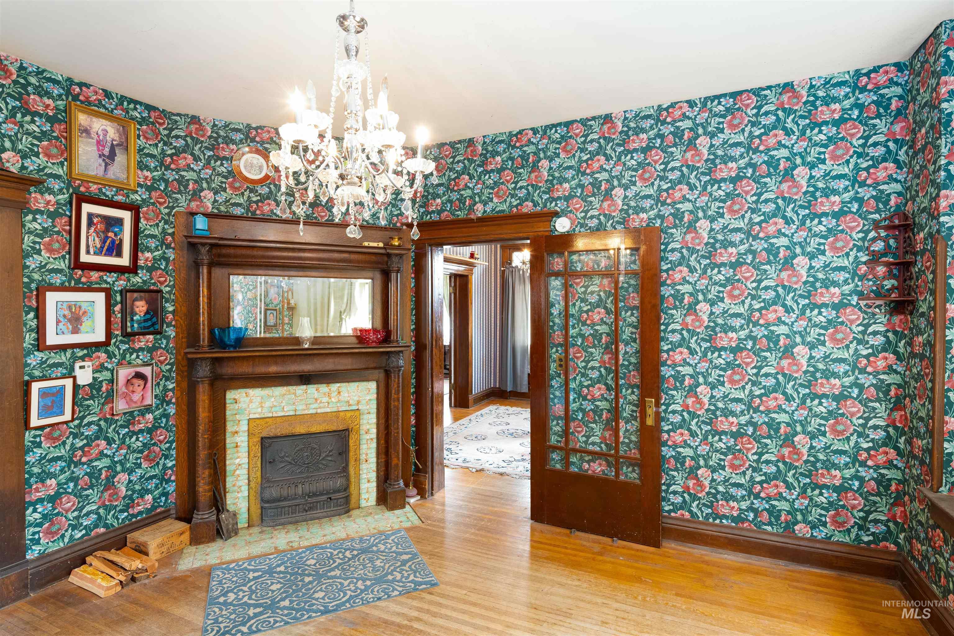 507 7th Avenue Lewiston, ID 83501 - Photo 12 of 30 Unfurnished living room featuring wallpapered walls, wood finished floors, a chandelier, and a fireplace with flush hearth