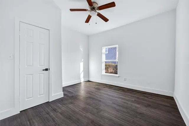 an empty room with wooden floor closet and windows
