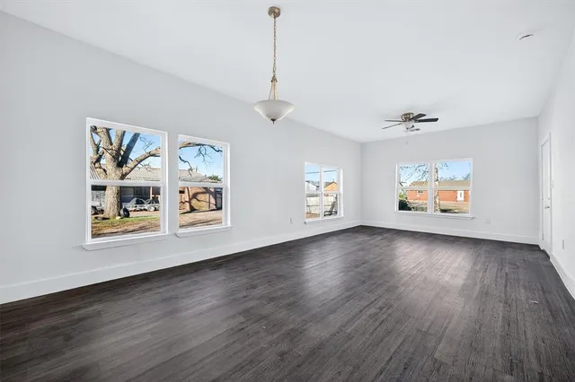a view of an empty room with window and wooden floor