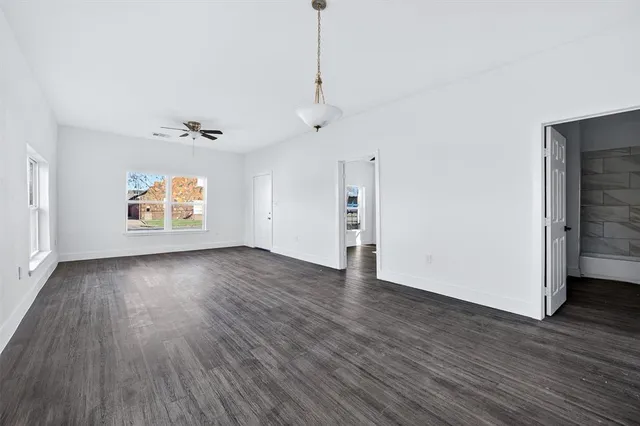 a view of an empty room with window and wooden floor