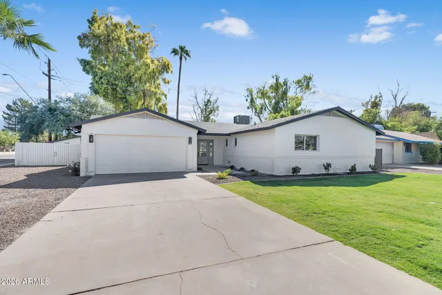 a front view of house with yard and trees in the background
