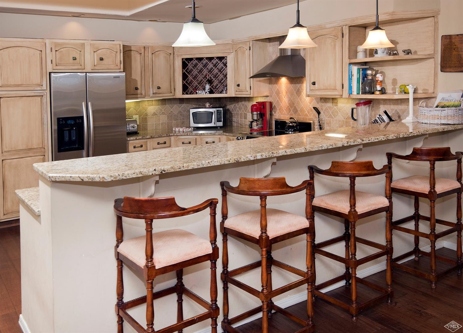 972 Eagle Drive Avon, CO 81620 - Photo 12 of 25 a kitchen with stainless steel appliances kitchen island granite countertop a table chairs in it and wooden floors