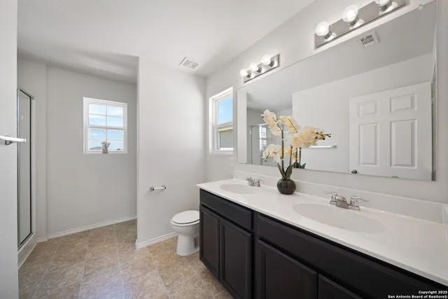 a bathroom with a double vanity sink toilet and mirror