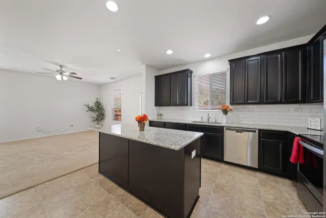 a kitchen with kitchen island granite countertop a sink dishwasher stove and cabinets
