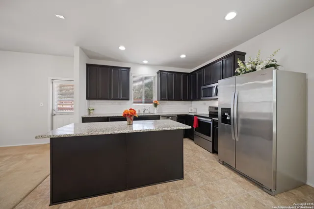 a kitchen with kitchen island a counter top space cabinets and stainless steel appliances