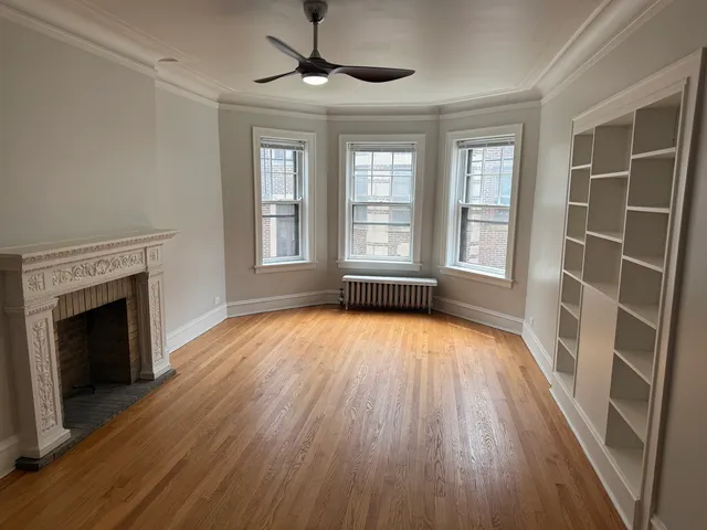an empty room with wooden floor fireplace and windows