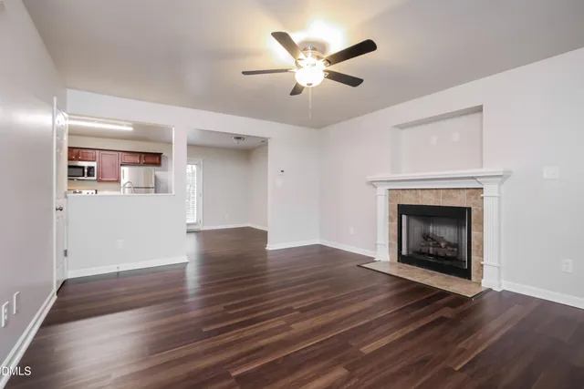 a view of an empty room with wooden floor fireplace and a window
