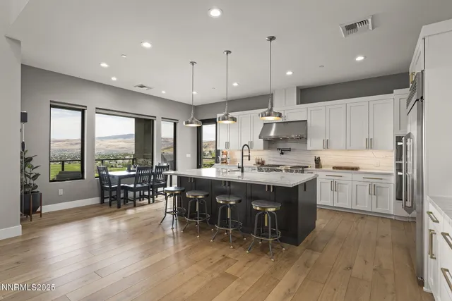 a large kitchen with stainless steel appliances granite countertop a lot of counter space and wooden floor