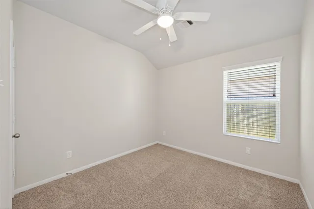 an empty room with a window and a fan