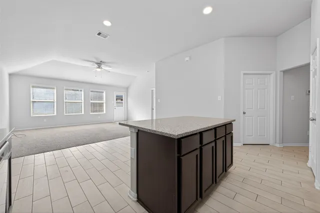 an empty room with kitchen view and wooden floor
