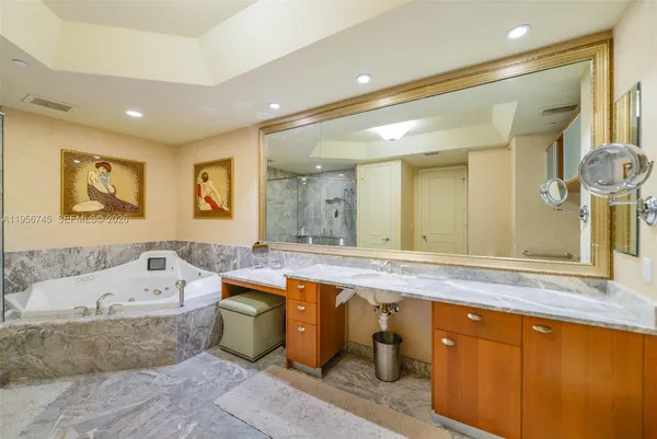 a bathroom with a granite countertop tub sink and mirror