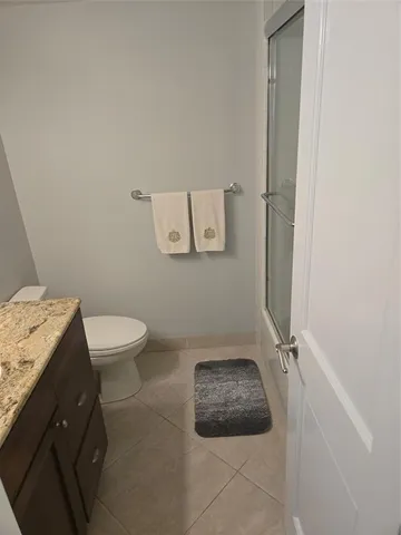a bathroom with a granite countertop sink and a toilet