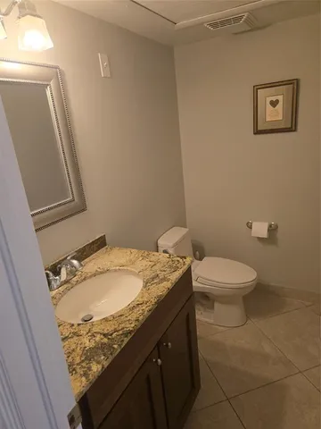 a bathroom with a granite countertop toilet and a sink