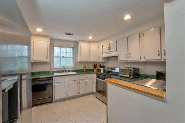 a kitchen with stainless steel appliances granite countertop white cabinets and a window