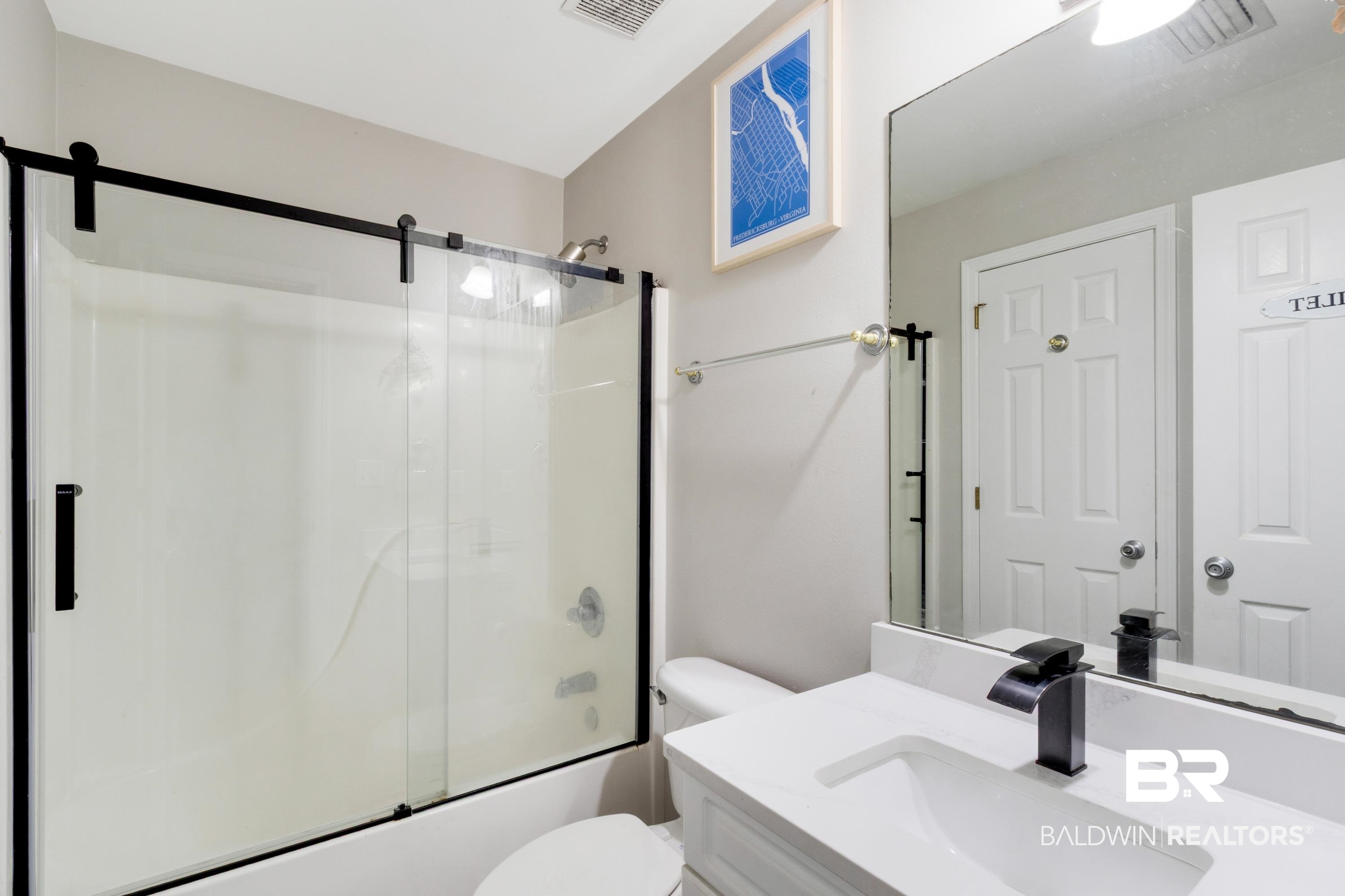 25957 Canal Road, Unit 208 Orange Beach, AL 36561 - Photo 16 of 28 Modern bathroom featuring a barn-door style glass shower enclosure, white tub, white vanity with integrated sink, matte black faucet, and large wall-mounted mirror