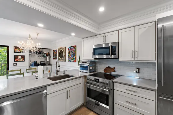 a kitchen with stainless steel appliances granite countertop a sink a stove a microwave a refrigerator and cabinets