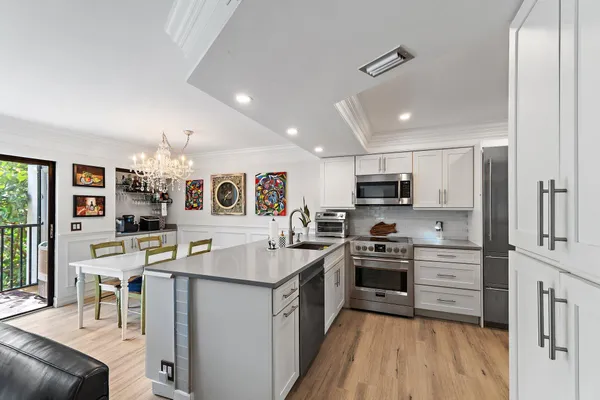 a kitchen with stainless steel appliances granite countertop a stove top oven a sink a dining table and chairs