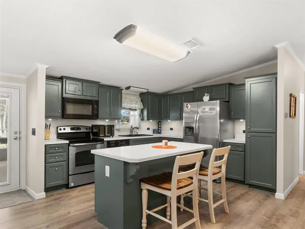 a kitchen with a refrigerator a stove top oven a sink dishwasher and white cabinets with wooden floor