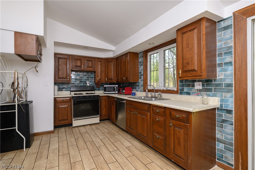 3055 Polly Road Ravenna, OH 44266 - Photo 8 of 25 Kitchen featuring vaulted ceiling, stainless steel appliances, tasteful backsplash, sink, and light wood-type flooring