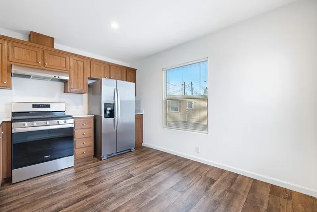 a kitchen with granite countertop a refrigerator and a stove top oven