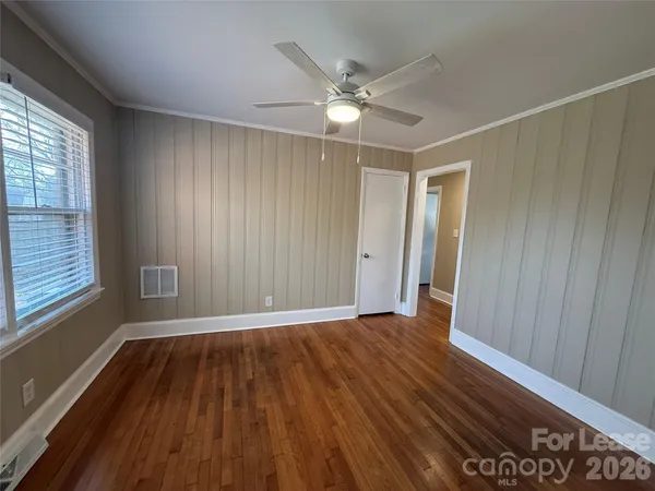a view of an empty room with wooden floor and a window