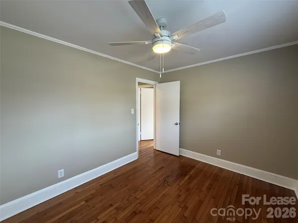 an empty room with wooden floor and fan