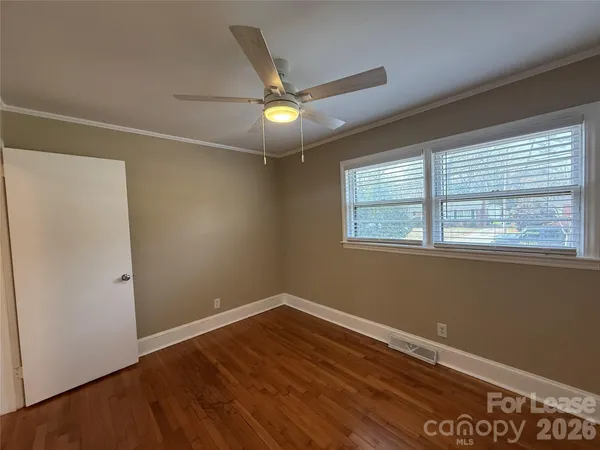 a view of empty room with wooden floor and fan