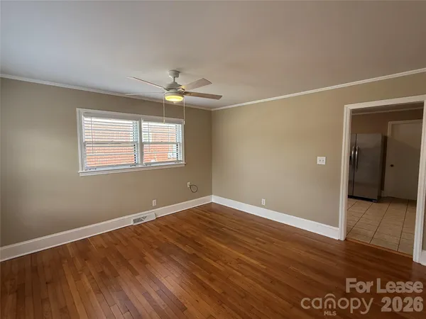 an empty room with wooden floor chandelier fan and windows