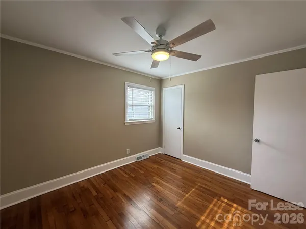 an empty room with wooden floor fan and windows