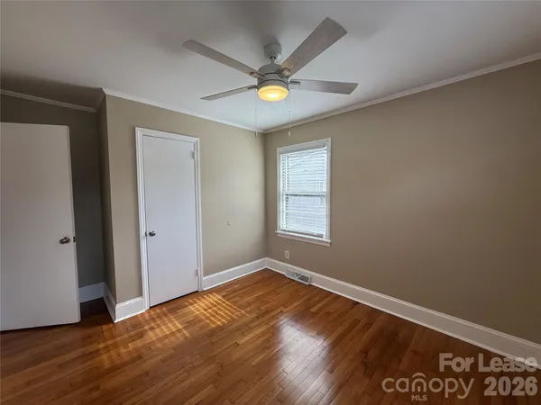 a view of empty room with wooden floor and fan
