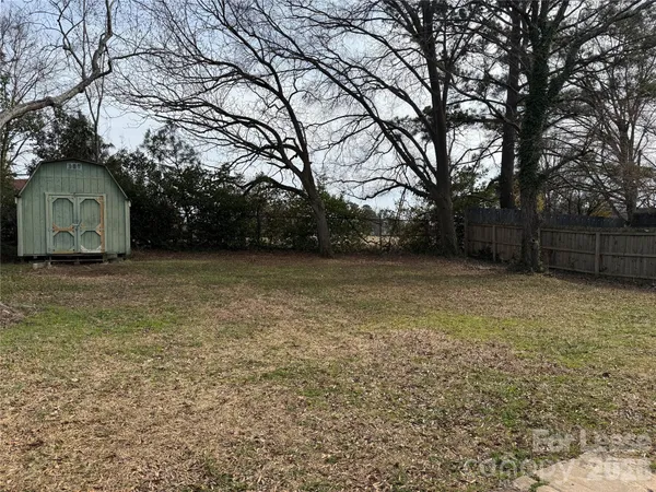 a view of a large house with a large tree and wooden fence