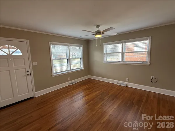 a view of an empty room with wooden floor and a window
