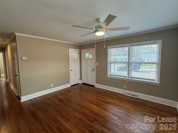 a view of an empty room with wooden floor and a window