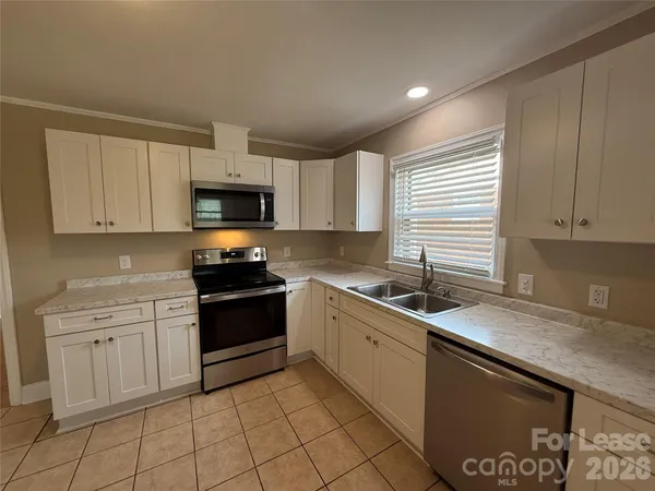 a kitchen with granite countertop white cabinets sink and stainless steel appliances