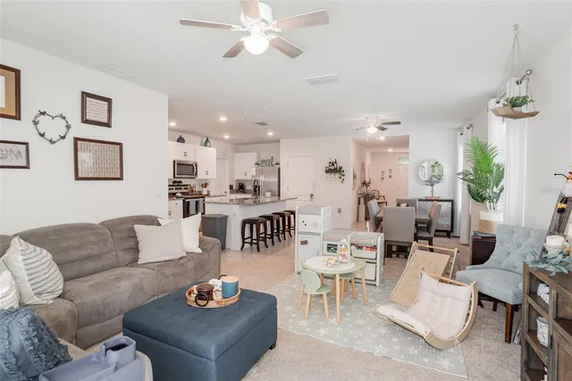 a living room with furniture kitchen view and a chandelier